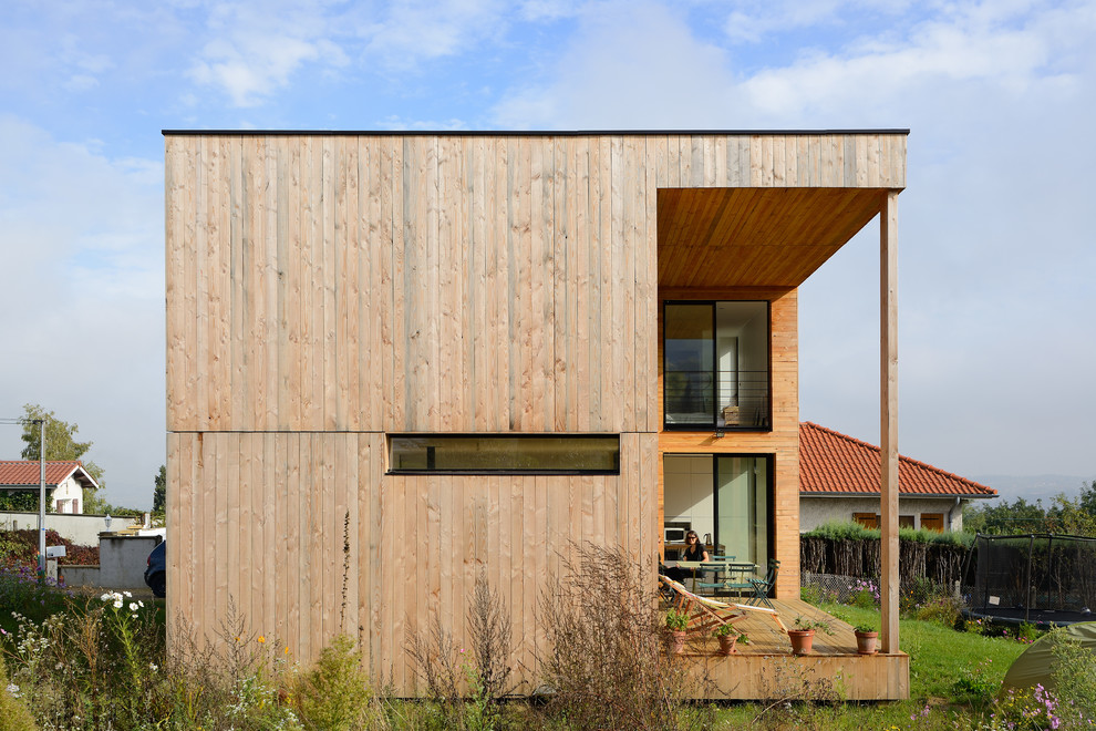 This is an example of a large contemporary two-storey exterior in Lyon with wood siding and a flat roof.