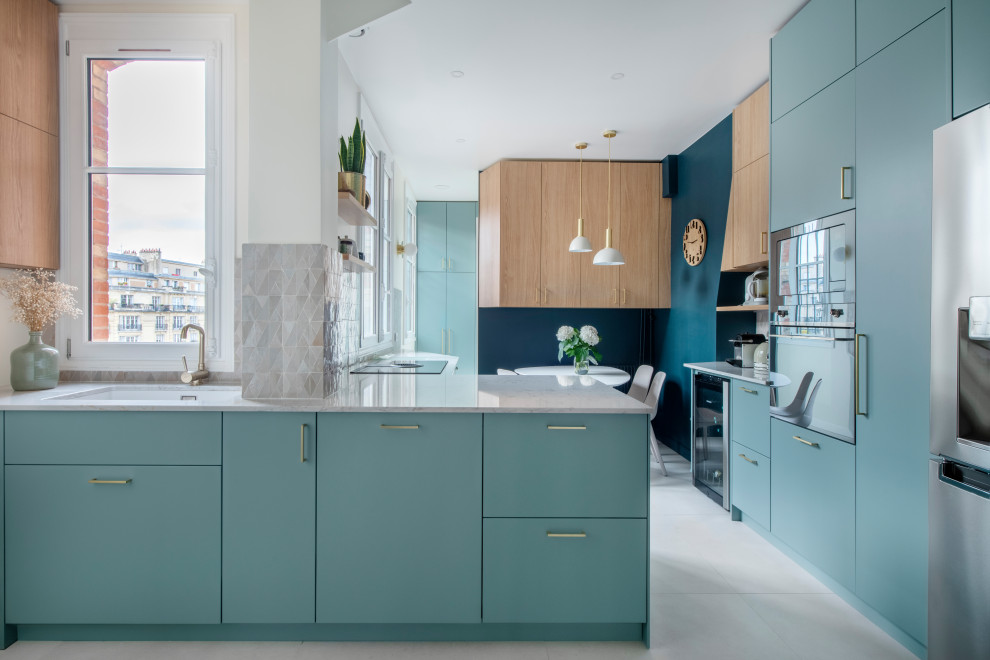 Contemporary u-shaped eat-in kitchen in Paris with an undermount sink, flat-panel cabinets, blue cabinets, marble benchtops, stainless steel appliances, a peninsula, white floor and multi-coloured benchtop.