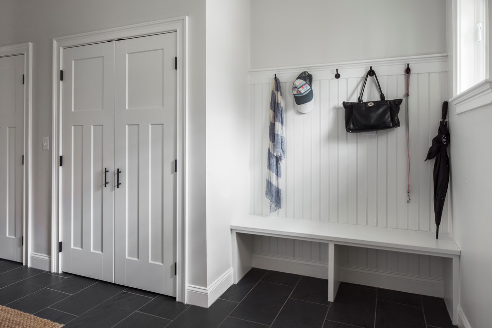 This is an example of a mid-sized transitional mudroom in Boston with white walls, slate floors, a single front door and a light wood front door.
