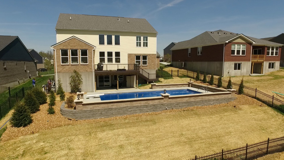 Modelo de piscina natural contemporánea grande rectangular en patio trasero con losas de hormigón