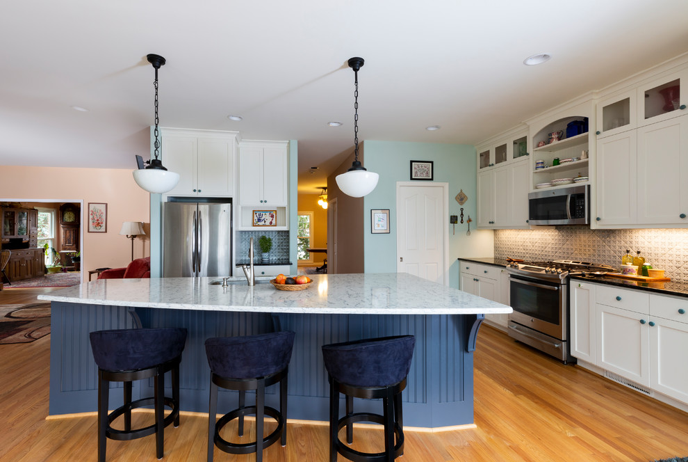 Mid-sized contemporary single-wall eat-in kitchen in Other with an undermount sink, shaker cabinets, white cabinets, blue splashback, stainless steel appliances, medium hardwood floors, with island, brown floor and black benchtop.