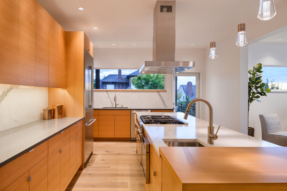 Inspiration for a large contemporary l-shaped eat-in kitchen in Seattle with a single-bowl sink, flat-panel cabinets, light wood cabinets, quartz benchtops, white splashback, stone slab splashback, stainless steel appliances, light hardwood floors, with island and white benchtop.