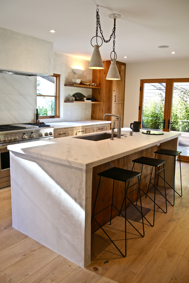 Large contemporary galley eat-in kitchen in Los Angeles with a double-bowl sink, recessed-panel cabinets, distressed cabinets, marble benchtops, white splashback, terra-cotta splashback, stainless steel appliances, light hardwood floors and with island.