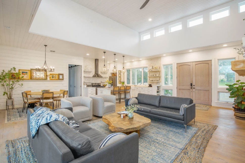 Mid-sized country open concept living room in Austin with white walls, light hardwood floors, a two-sided fireplace, a stone fireplace surround, white floor, coffered and planked wall panelling.