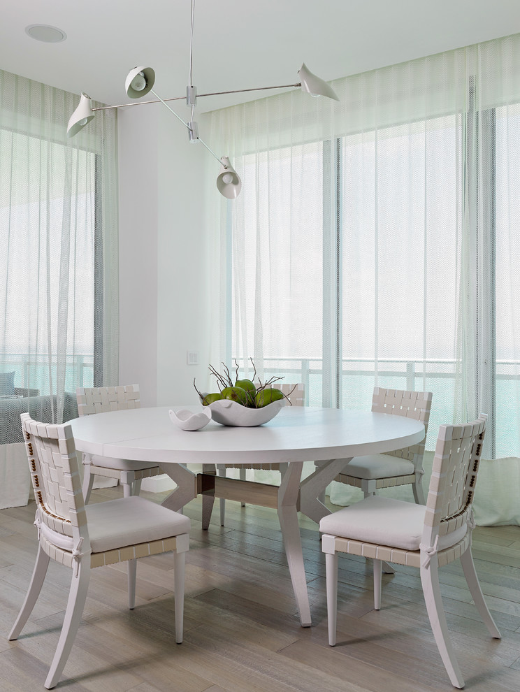 This is an example of a beach style dining room in Miami with white walls and medium hardwood floors.
