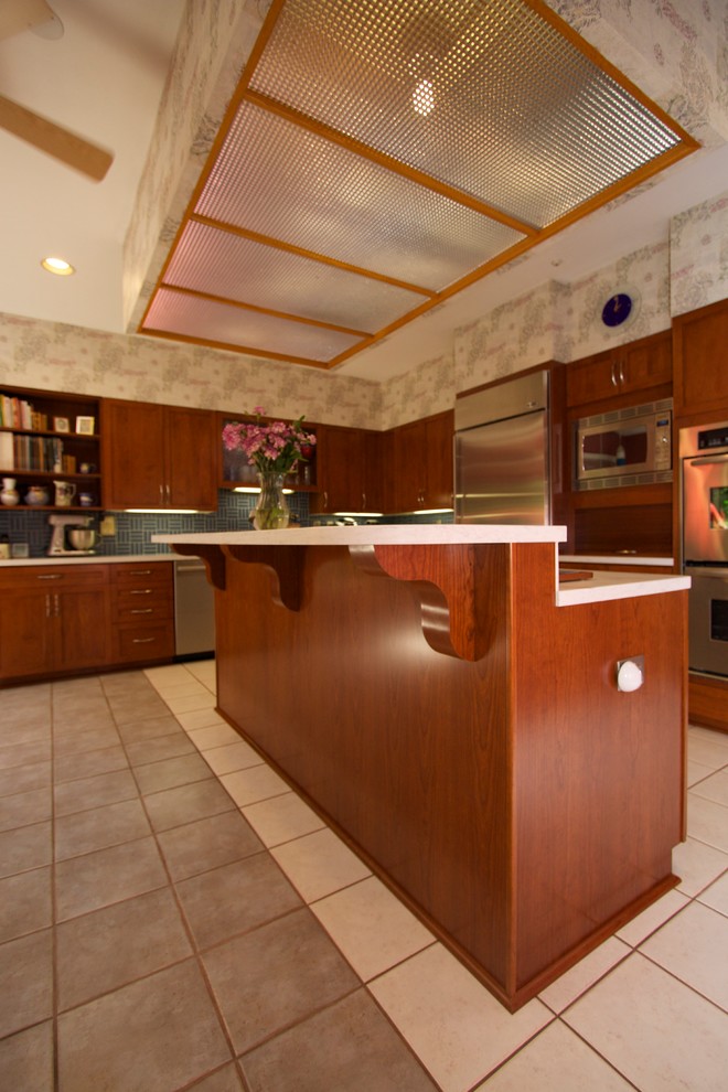 Example of a transitional l-shaped ceramic tile open concept kitchen design in Baltimore with an undermount sink, recessed-panel cabinets, medium tone wood cabinets, solid surface countertops, blue backsplash, ceramic backsplash, stainless steel appliances and an island