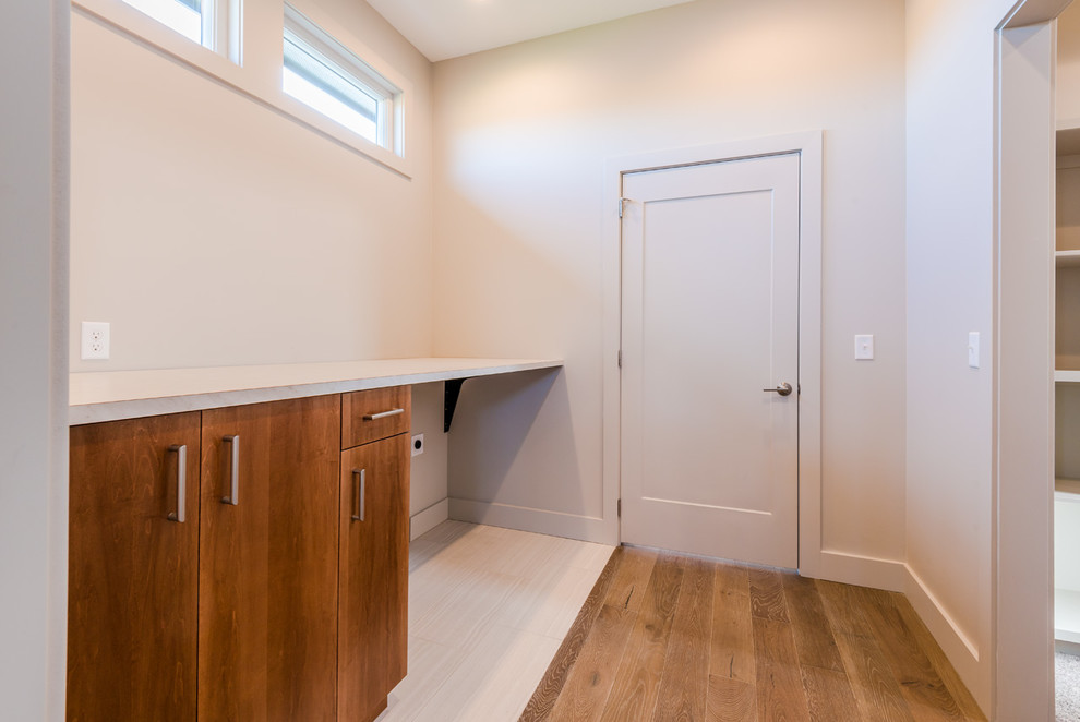Inspiration for a mid-sized transitional single-wall ceramic tile home design remodel with flat-panel cabinets, light wood cabinets, laminate countertops, gray walls and a side-by-side washer/dryer