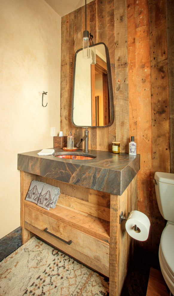 Photo of a country powder room in Salt Lake City with flat-panel cabinets, medium wood cabinets, a two-piece toilet, beige walls, dark hardwood floors, an undermount sink, brown floor and grey benchtops.