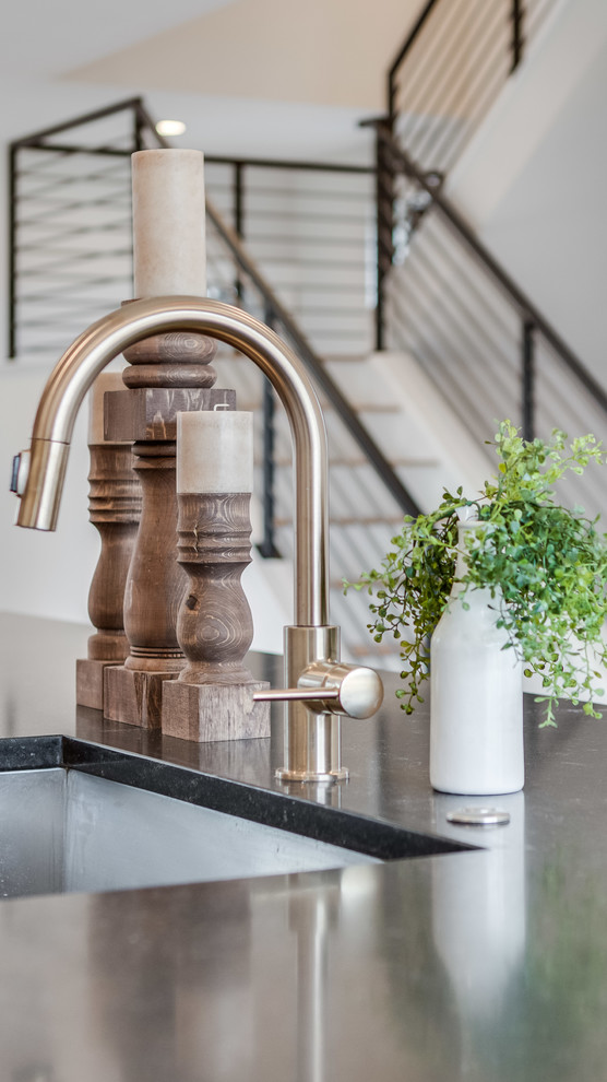 Example of a mid-sized farmhouse galley light wood floor and beige floor eat-in kitchen design in Denver with an undermount sink, shaker cabinets, white cabinets, white backsplash, ceramic backsplash, stainless steel appliances, an island and black countertops