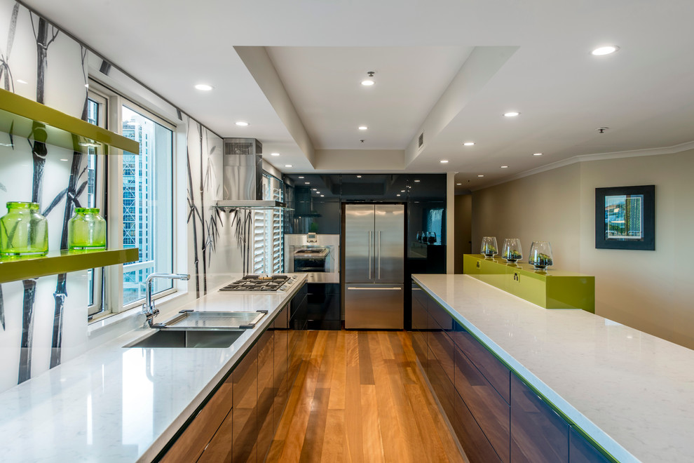 Inspiration for a mid-sized contemporary galley eat-in kitchen in Brisbane with a single-bowl sink, flat-panel cabinets, blue cabinets, quartz benchtops, white splashback, glass sheet splashback, stainless steel appliances, medium hardwood floors and with island.