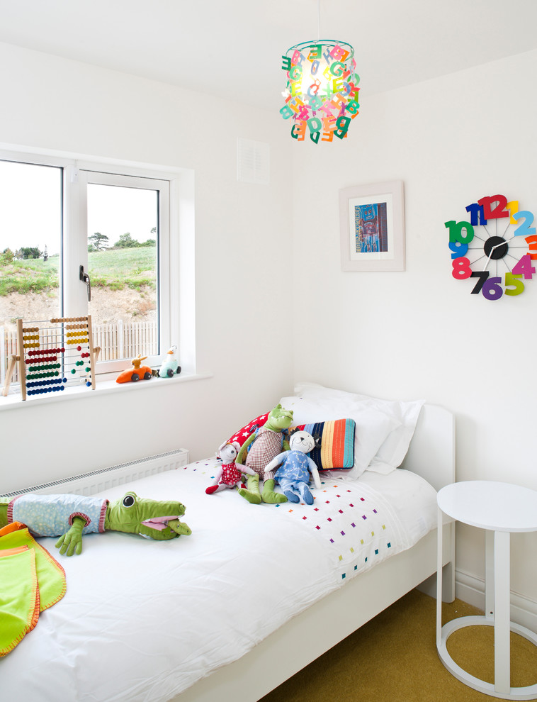 This is an example of a transitional gender-neutral kids' bedroom for kids 4-10 years old in Dublin with white walls, carpet and yellow floor.