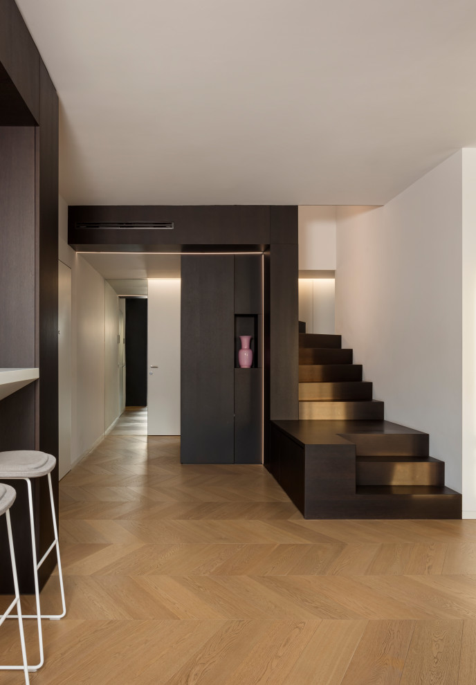 Идея дизайна: п-образная лестница среднего размера с крашенными деревянными ступенями, крашенными деревянными подступенками, стеклянными перилами и панелями на части стены