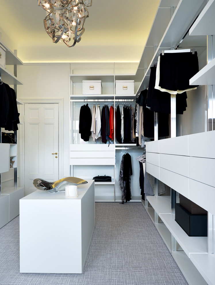 This is an example of a mid-sized modern gender-neutral walk-in wardrobe in Stockholm with open cabinets and carpet.