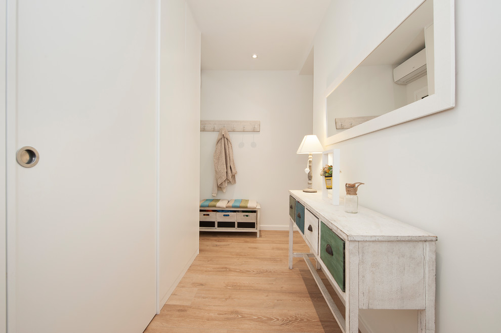 Ejemplo de recibidores y pasillos escandinavos de tamaño medio con paredes blancas, suelo de madera en tonos medios y suelo marrón
