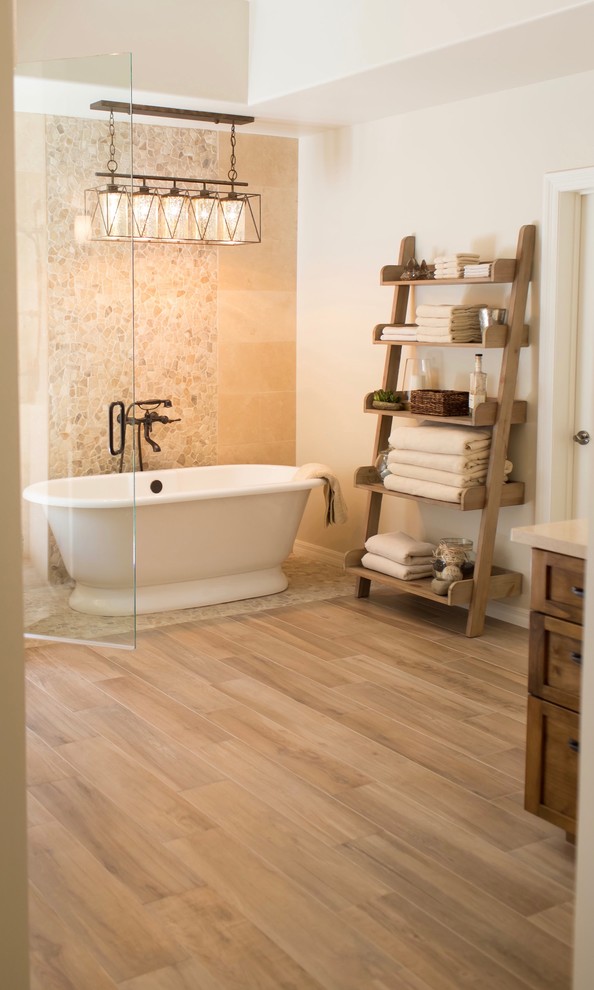 Inspiration for a mid-sized mediterranean master bathroom in Phoenix with shaker cabinets, medium wood cabinets, a freestanding tub, a one-piece toilet, beige tile, travertine, beige walls, porcelain floors, an undermount sink, marble benchtops, beige floor and a hinged shower door.