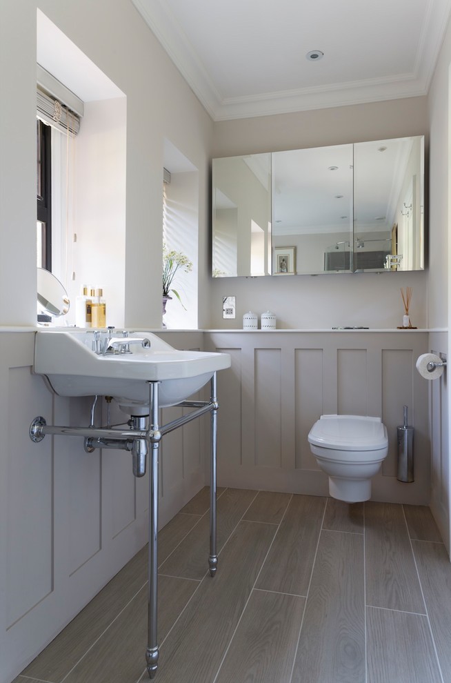 Mid-sized transitional bathroom in London with a wall-mount toilet, a console sink and grey floor.