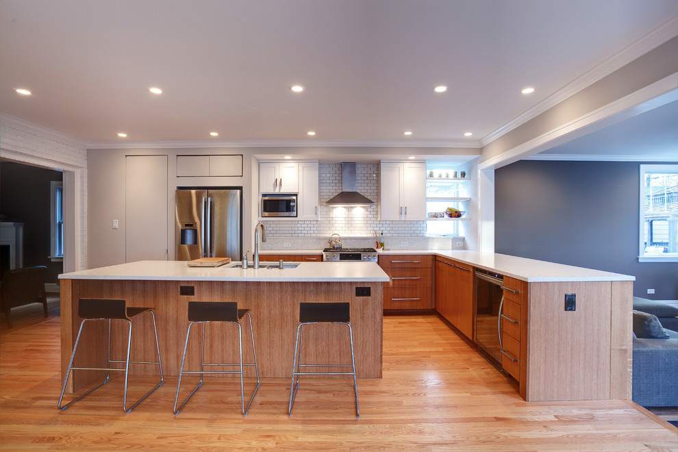 Inspiration for a mid-sized contemporary l-shaped eat-in kitchen in Chicago with a double-bowl sink, flat-panel cabinets, medium wood cabinets, quartz benchtops, white splashback, ceramic splashback, stainless steel appliances, medium hardwood floors and with island.
