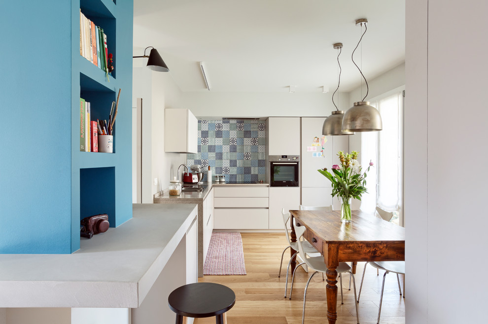Eclectic l-shaped eat-in kitchen in Other with a double-bowl sink, flat-panel cabinets, white cabinets, multi-coloured splashback, panelled appliances, medium hardwood floors, no island, brown floor and brown benchtop.