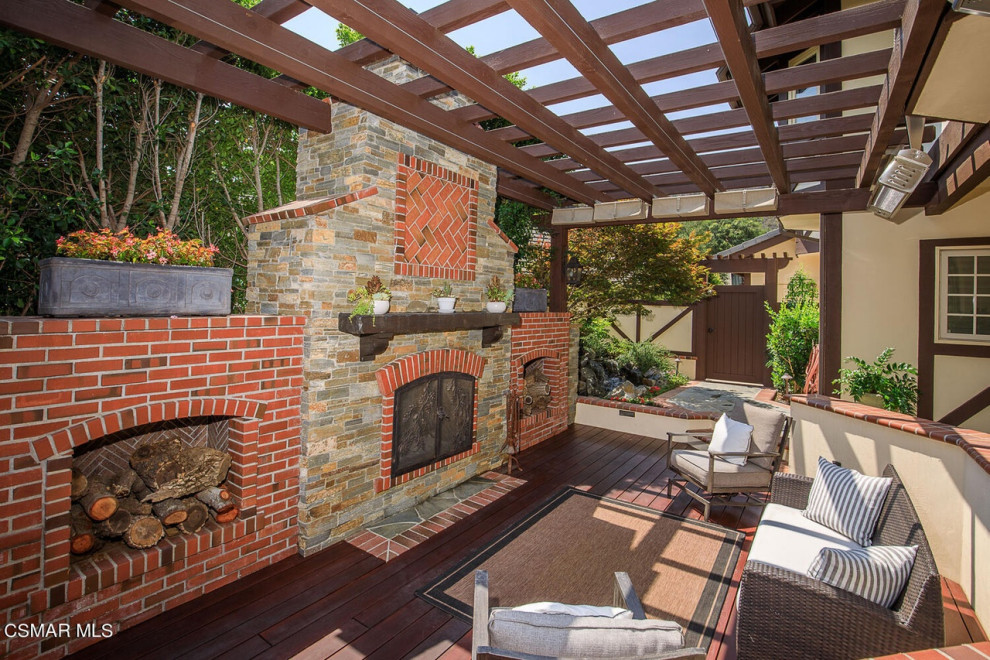 Inspiration for an expansive traditional back formal full sun garden for summer in Los Angeles with a wood fence, a fireplace and decking.