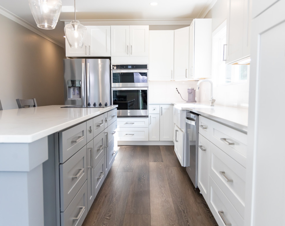 Exempel på ett litet klassiskt vit linjärt vitt kök och matrum, med en nedsänkt diskho, luckor med profilerade fronter, vita skåp, marmorbänkskiva, vitt stänkskydd, rostfria vitvaror, vinylgolv, en köksö och brunt golv