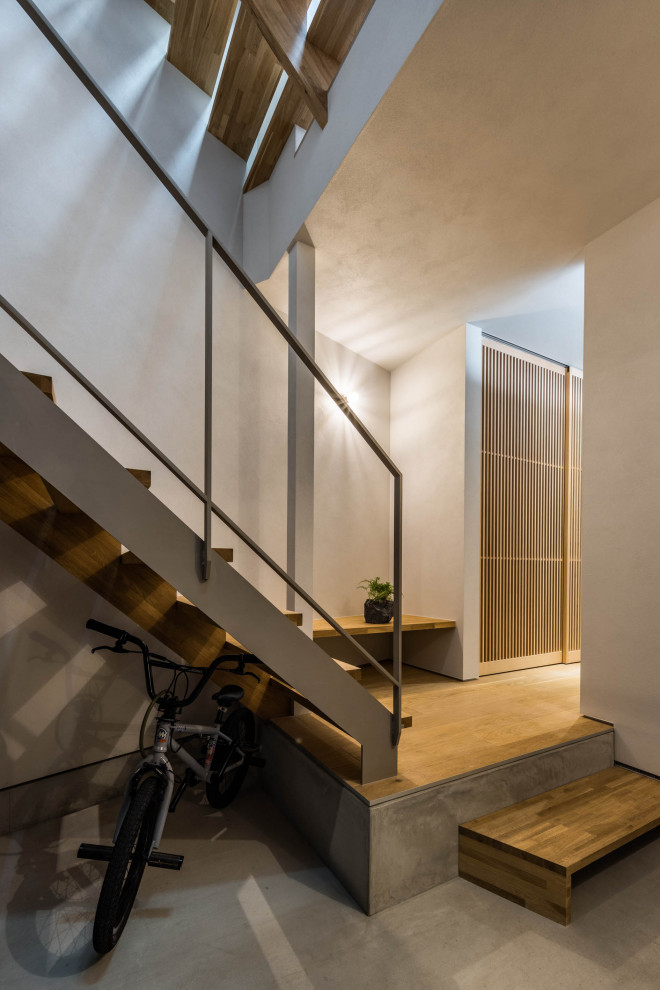На фото: лестница в современном стиле с деревянными ступенями, металлическими перилами и кладовкой или шкафом под ней без подступенок с
