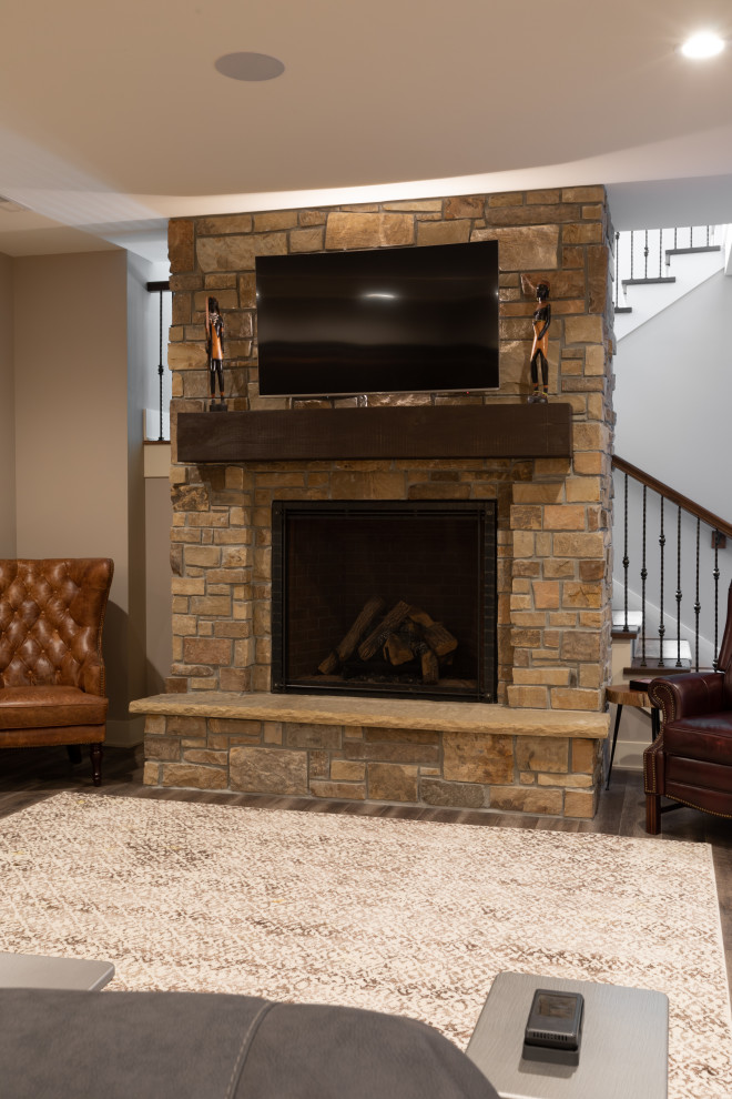 Design ideas for a mid-sized country fully buried basement in Omaha with grey walls, dark hardwood floors, a standard fireplace, a stone fireplace surround and grey floor.