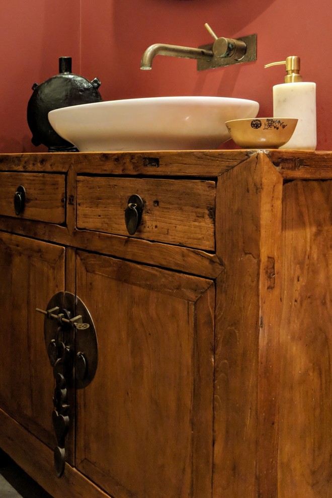 Design ideas for a small transitional powder room in Sydney with furniture-like cabinets, medium wood cabinets, red walls, porcelain floors, a vessel sink, wood benchtops and black floor.