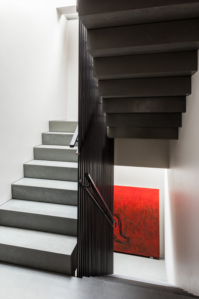 Inspiration for a large contemporary concrete u-shaped staircase in London with concrete risers and metal railing.