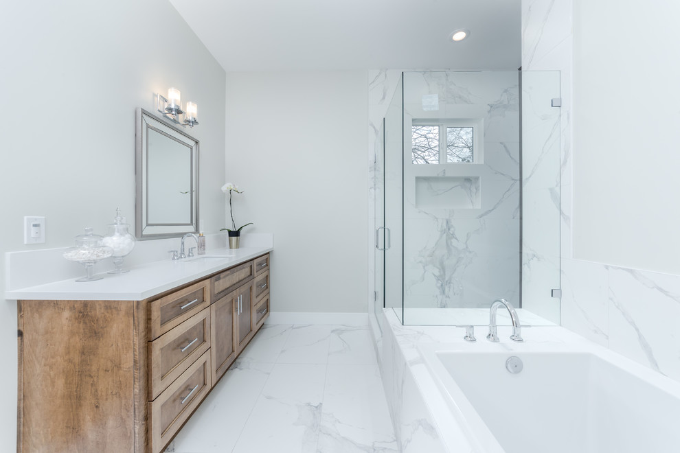 Design ideas for a mid-sized contemporary master bathroom in Sacramento with flat-panel cabinets, white cabinets, a drop-in tub, an alcove shower, a one-piece toilet, gray tile, marble, white walls, marble floors, an integrated sink, marble benchtops, white floor, a hinged shower door and white benchtops.