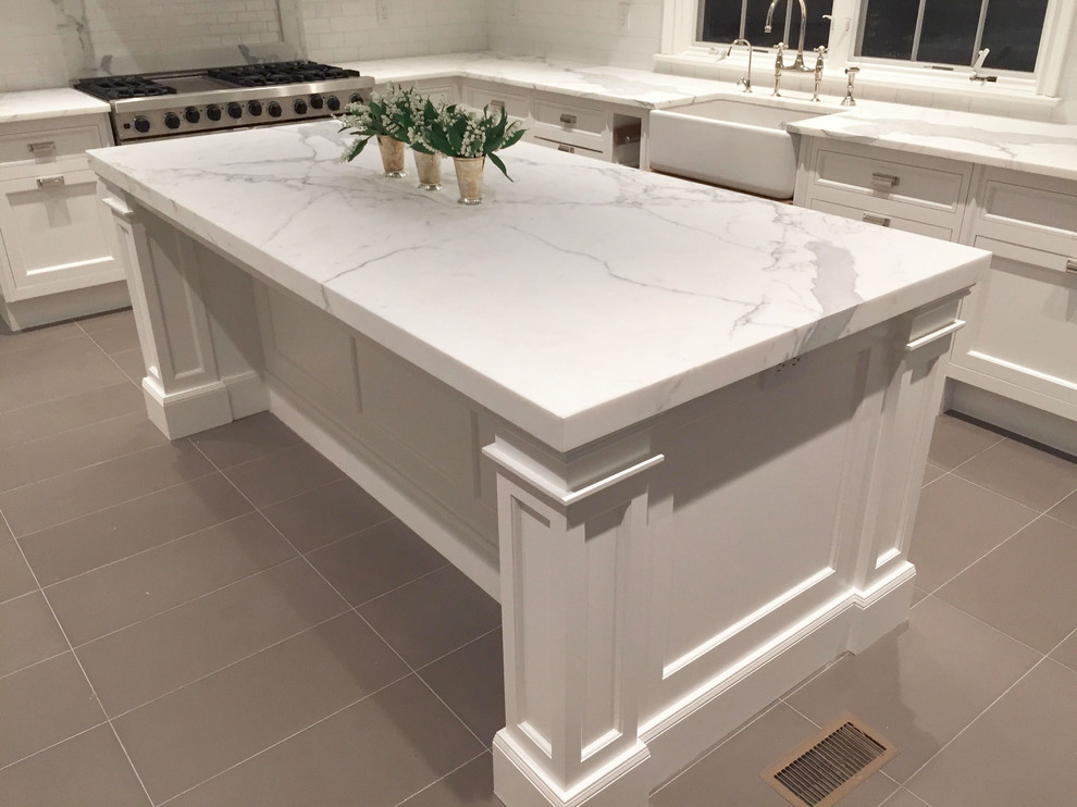 Large transitional l-shaped beige floor eat-in kitchen photo with a farmhouse sink, shaker cabinets, white cabinets, white backsplash, stainless steel appliances and an island