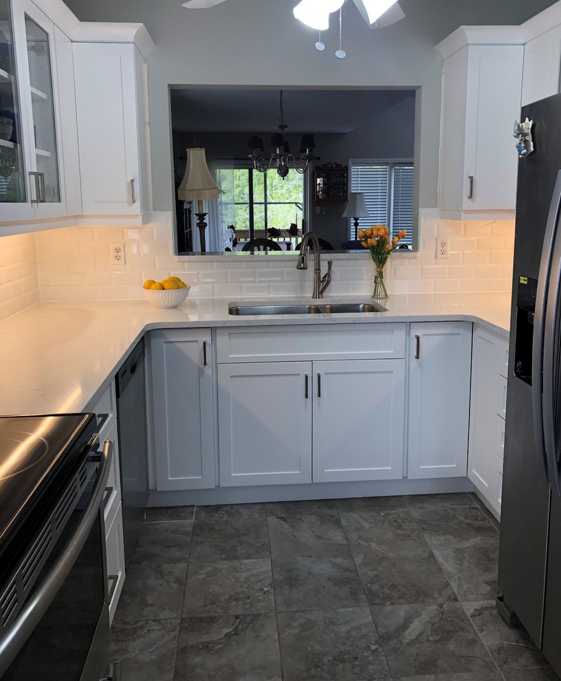 Small contemporary u-shaped separate kitchen in Toronto with an undermount sink, shaker cabinets, white cabinets, quartz benchtops, white splashback, ceramic splashback, stainless steel appliances, porcelain floors, no island, beige floor and white benchtop.