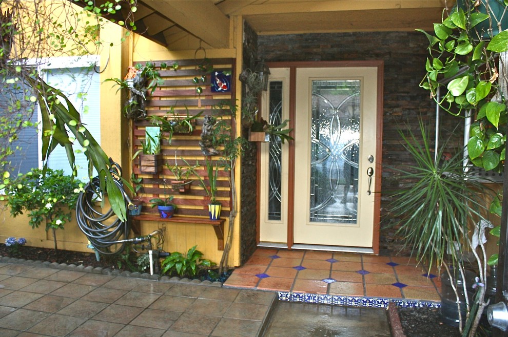 Photo of a small tropical courtyard patio in Los Angeles with a vertical garden, tile and a roof extension.