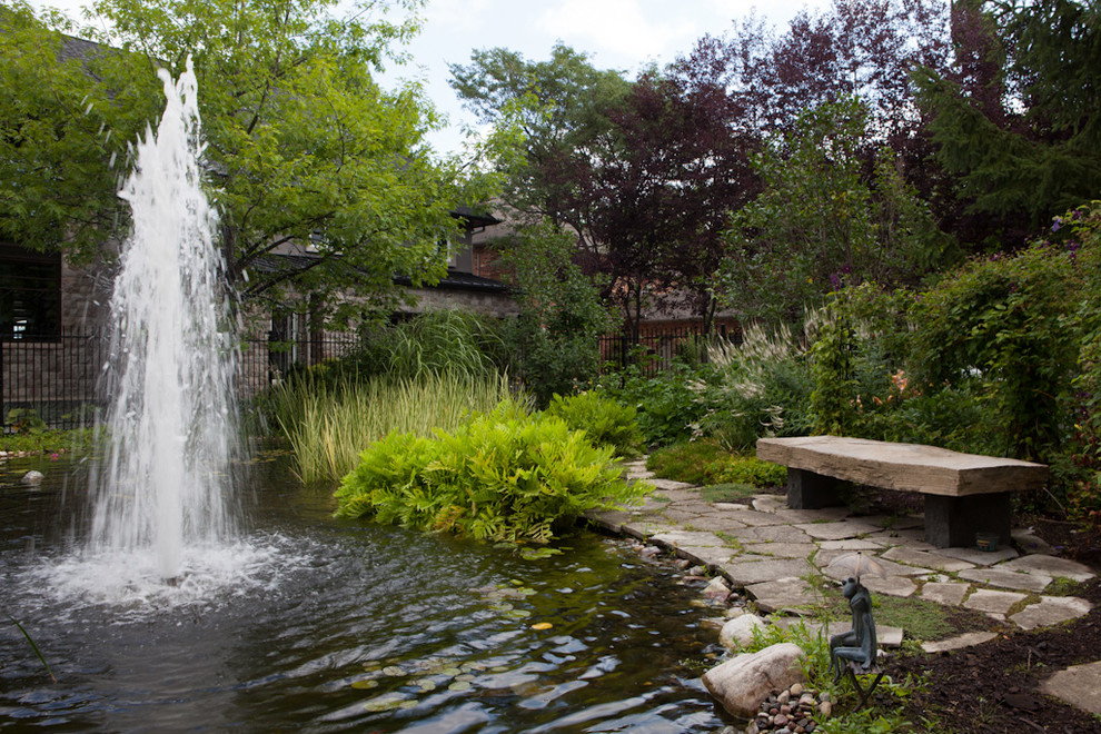 This is an example of a contemporary garden in Ottawa with a water feature and natural stone pavers.