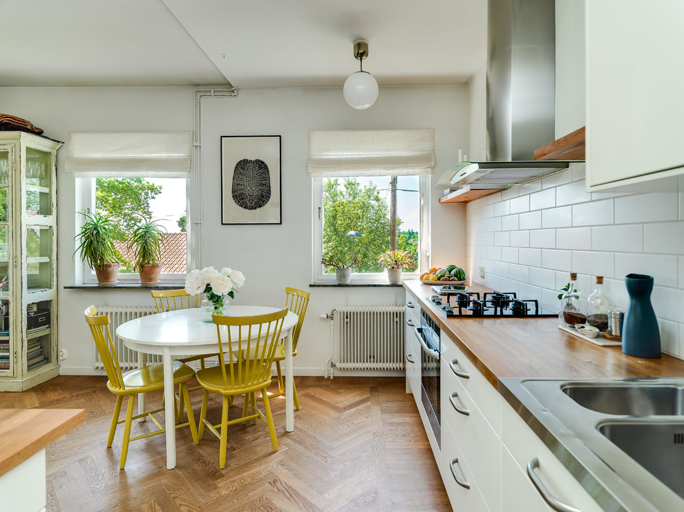 This is an example of a mid-sized scandinavian kitchen/dining combo in Stockholm with white walls and light hardwood floors.
