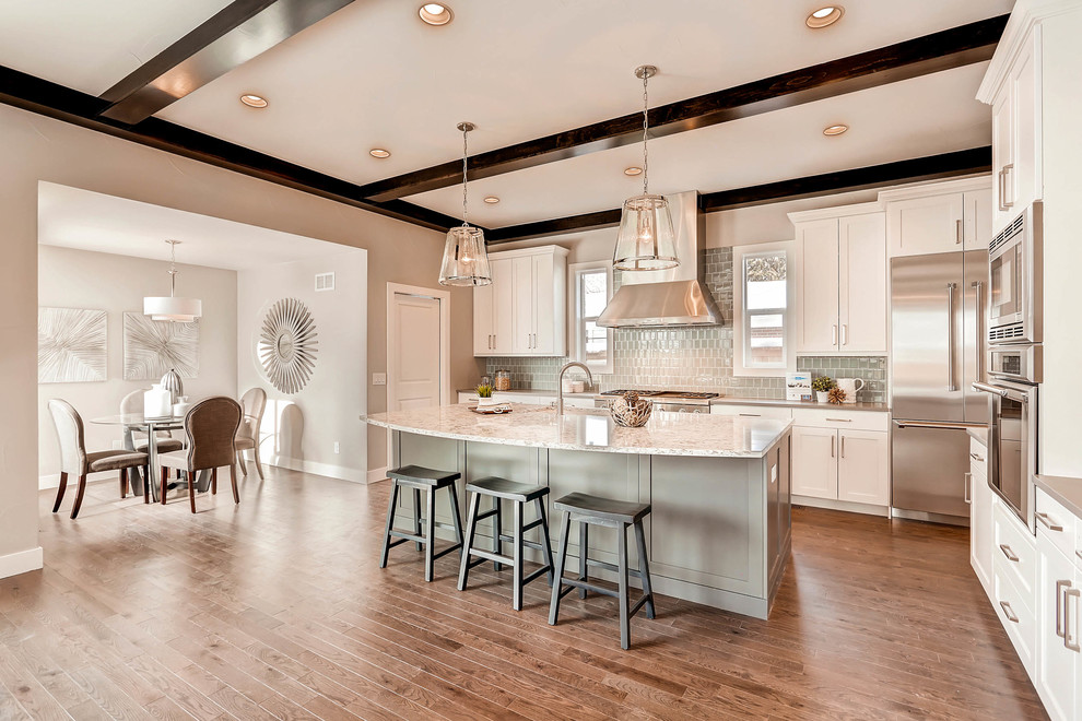 Example of a large transitional l-shaped medium tone wood floor open concept kitchen design in Denver with shaker cabinets, white cabinets, granite countertops, gray backsplash, glass tile backsplash, stainless steel appliances, an island and an undermount sink