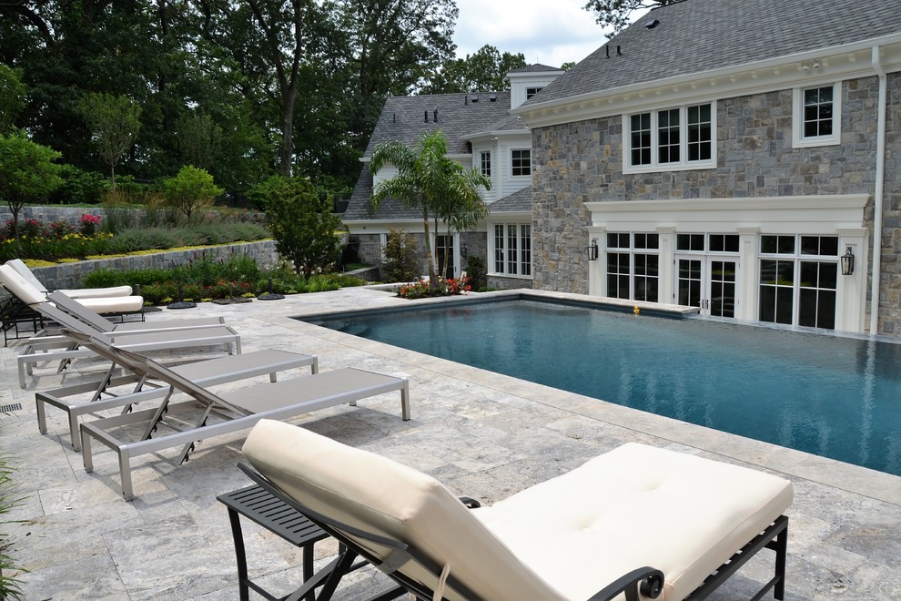 Inspiration for a large modern backyard rectangular infinity pool in New York with a pool house and natural stone pavers.