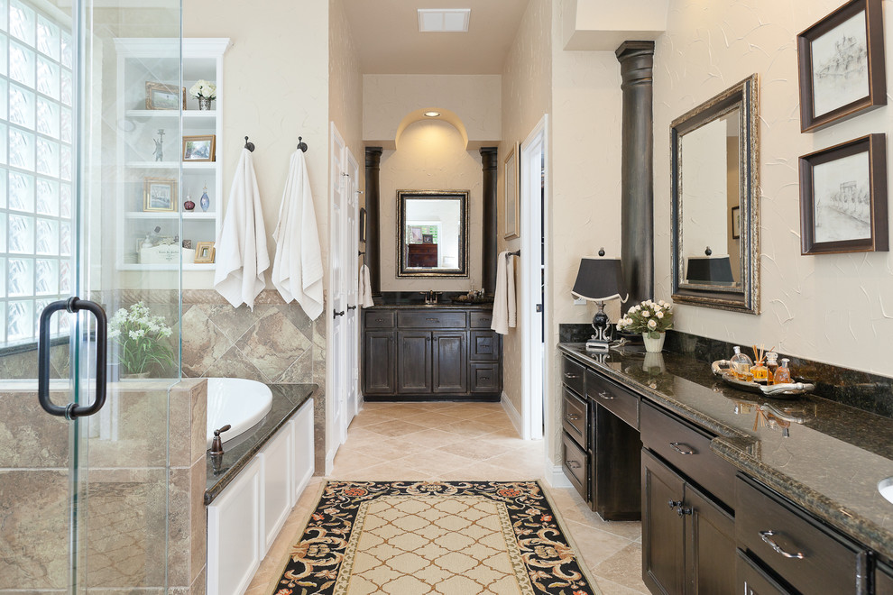 This is an example of a traditional bathroom in Houston with an undermount sink, recessed-panel cabinets, dark wood cabinets, a drop-in tub, a corner shower and beige tile.