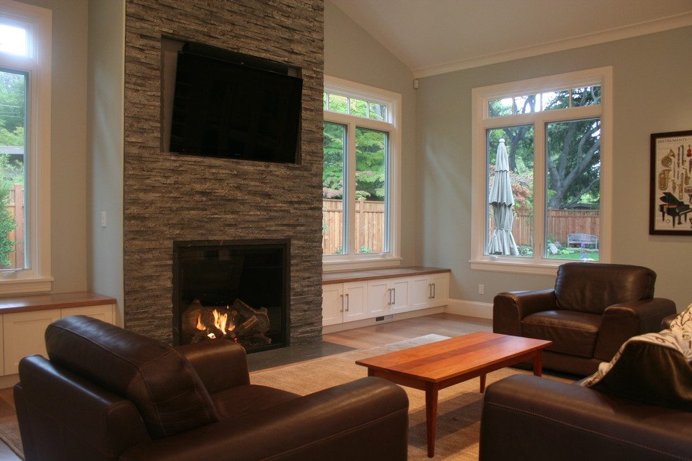 Photo of a mid-sized midcentury living room in San Francisco with green walls, medium hardwood floors, a standard fireplace, a stone fireplace surround and a wall-mounted tv.