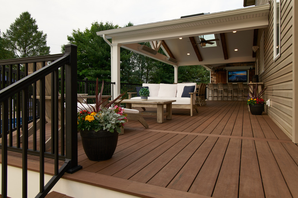 Photo of a mid-sized country backyard and ground level deck in Philadelphia with a roof extension and metal railing.