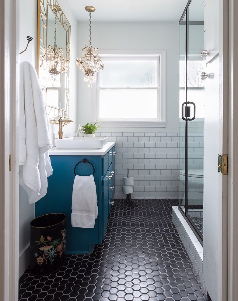 Photo of a traditional 3/4 bathroom in Austin with flat-panel cabinets, blue cabinets, a corner shower, white tile, subway tile, white walls, a vessel sink, black floor and a hinged shower door.