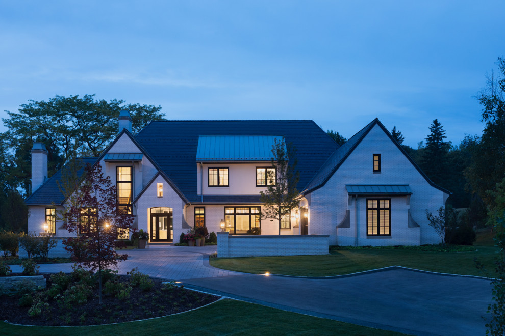 Idée de décoration pour une façade de maison blanche champêtre en brique avec un toit à deux pans et un toit noir.
