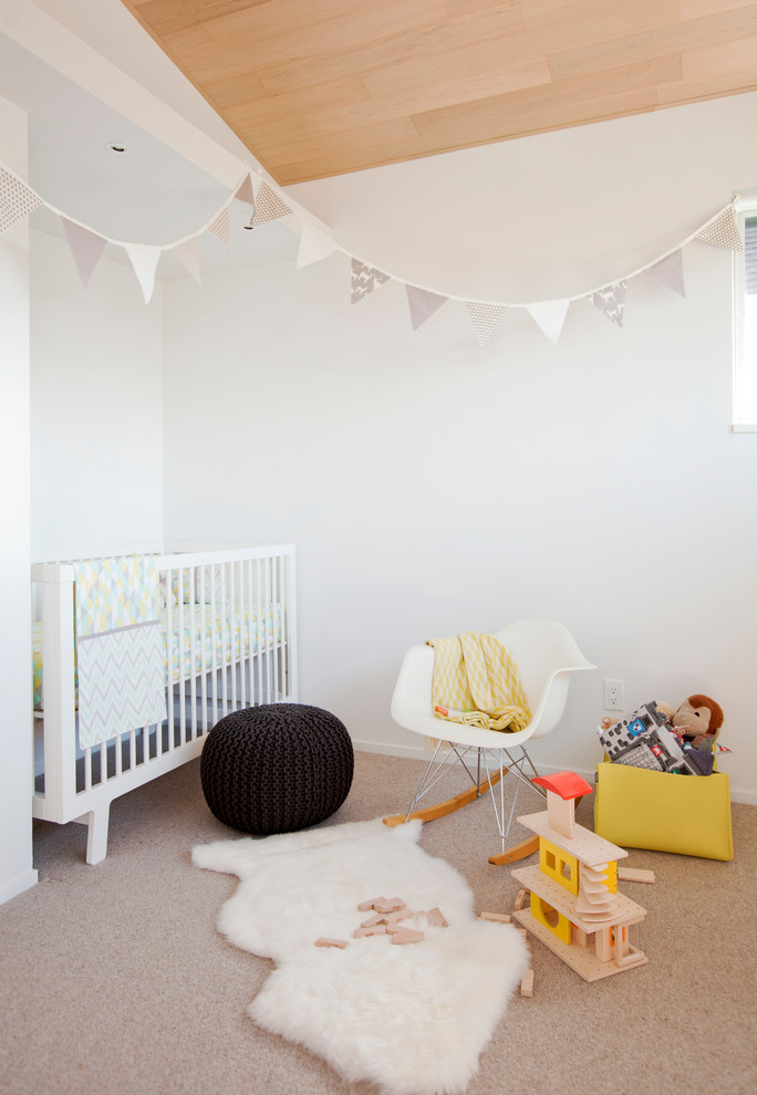 Scandinavian gender-neutral nursery in Vancouver with white walls, carpet and beige floor.