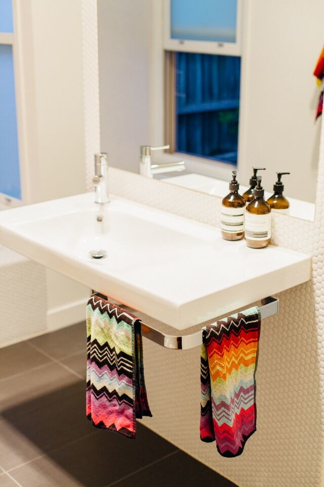 This is an example of a mid-sized transitional master bathroom in Melbourne with flat-panel cabinets, white cabinets, a drop-in tub, an alcove shower, a two-piece toilet, white tile, ceramic tile, white walls, porcelain floors, a trough sink, engineered quartz benchtops, grey floor, an open shower and white benchtops.