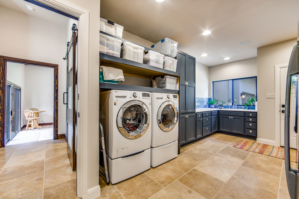 Design ideas for a large transitional l-shaped dedicated laundry room in Austin with an integrated sink, shaker cabinets, grey cabinets, granite benchtops, white walls, travertine floors, a side-by-side washer and dryer, beige floor and white benchtop.
