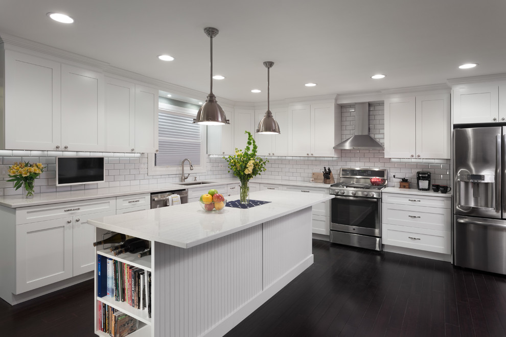 This is an example of a large modern l-shaped open plan kitchen in Chicago with an undermount sink, shaker cabinets, white cabinets, marble benchtops, white splashback, subway tile splashback, stainless steel appliances, dark hardwood floors and with island.