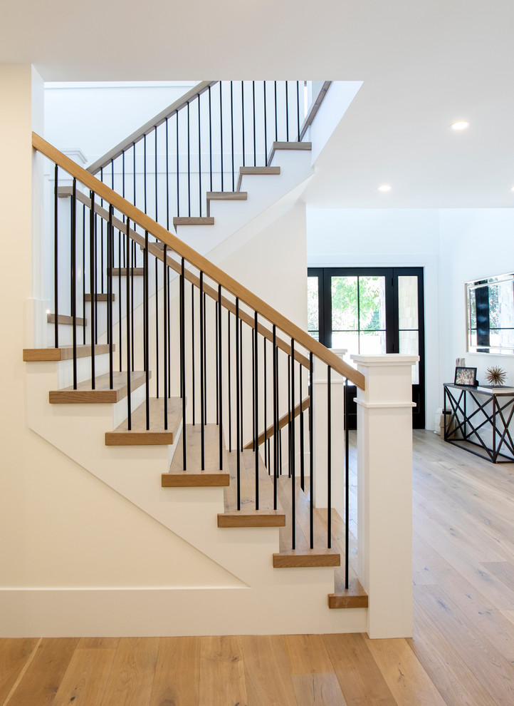 Photo of a large country wood u-shaped staircase in Vancouver with painted wood risers and wood railing.