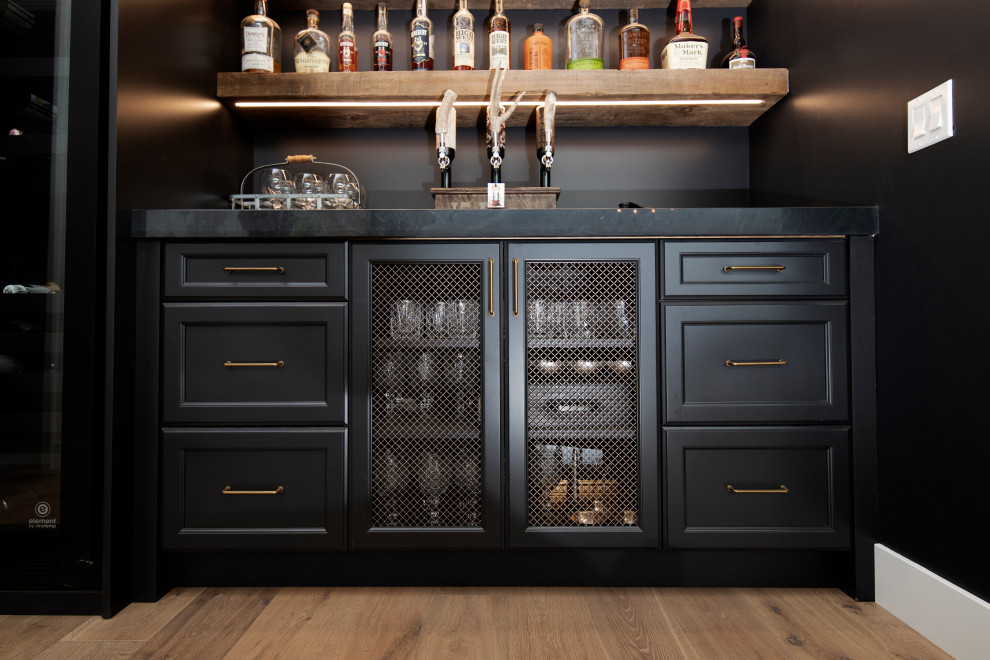 This is an example of a small modern single-wall home bar in San Diego with recessed-panel cabinets, black cabinets, granite benchtops, black splashback, medium hardwood floors and black benchtop.