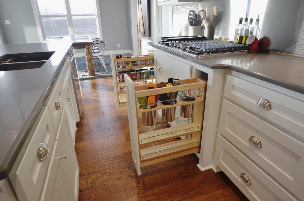 Inspiration for a large transitional l-shaped medium tone wood floor and brown floor open concept kitchen remodel in Kansas City with an undermount sink, shaker cabinets, white cabinets, quartz countertops, white backsplash, mosaic tile backsplash, stainless steel appliances, an island and gray countertops