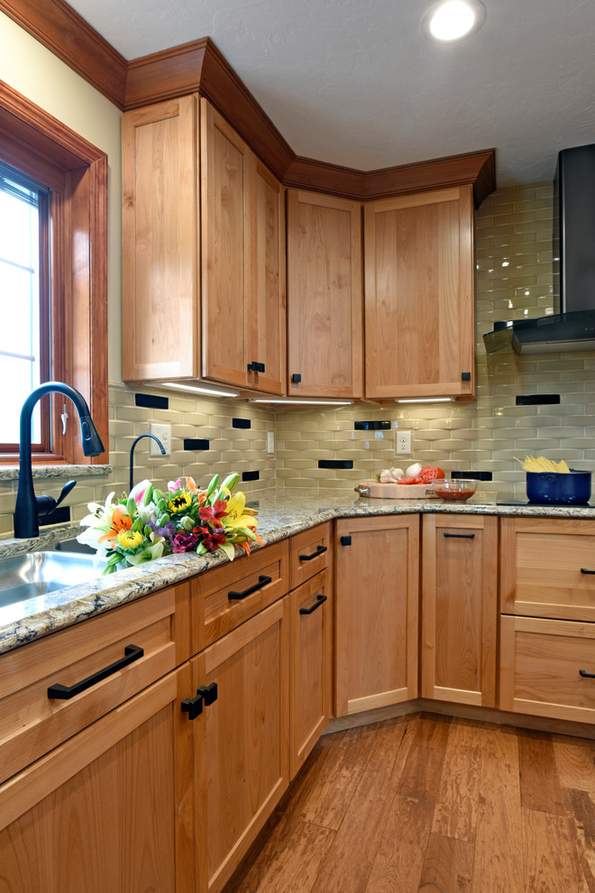 This is an example of a large transitional u-shaped separate kitchen in Other with an undermount sink, flat-panel cabinets, light wood cabinets, quartz benchtops, beige splashback, ceramic splashback, black appliances, medium hardwood floors, with island, brown floor and beige benchtop.