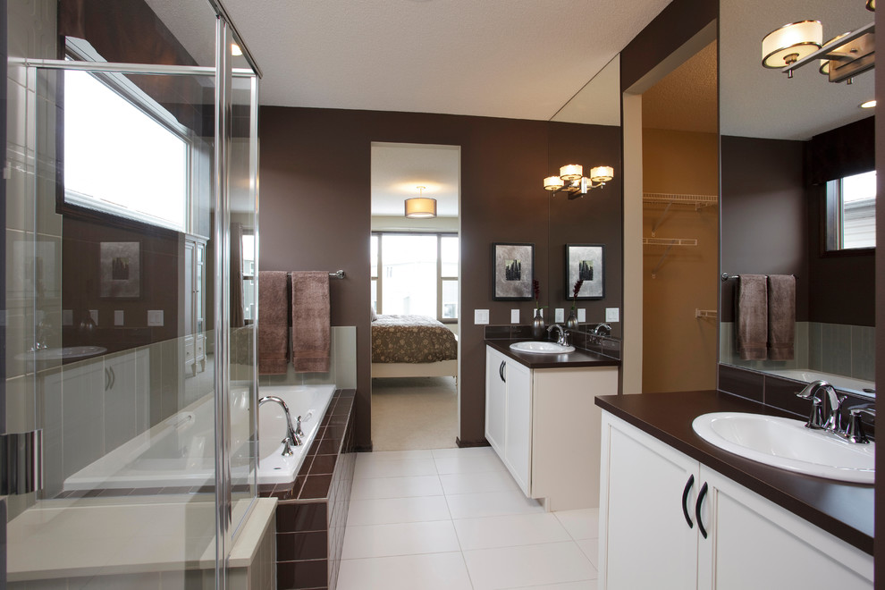 This is an example of a modern bathroom in Calgary with a drop-in sink, recessed-panel cabinets, white cabinets, a drop-in tub, a corner shower, brown tile and brown walls.